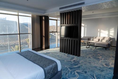 a bedroom with a bed and a living room with windows at فندق ديماس DEMAS Hotel in Khamis Mushayt