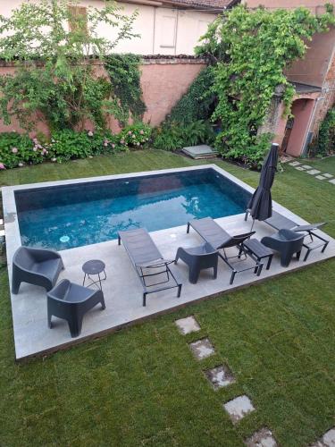 a swimming pool with chairs and a table and umbrella at Villa Lu alloggio con idromassaggio e piscina in Carignano