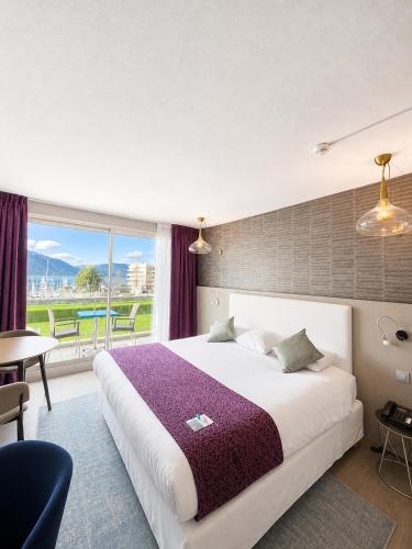 a hotel room with a large bed and a balcony at Logis Hôtel & Spa Marina d'Adelphia in Aix-les-Bains