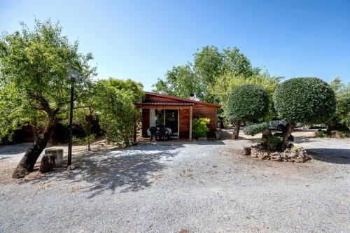 a small house with a porch and trees at Cabañas Cortijo el Helao in Pozo Alcón