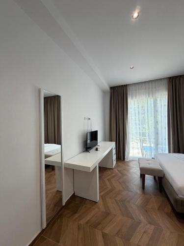 a bedroom with a bed and a desk with a television at Blue Days Villa 2 in Shkalle Stenojt