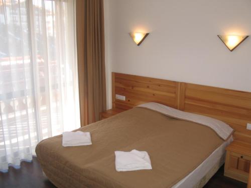 a bedroom with a bed with two towels on it at Winslow Infinity Aparthotel in Bansko