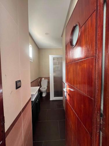 a bathroom with a toilet and a wooden door at Chic Villa - Pool - Wi-Fi -Parking - 3 Bedrooms in Sidi Bouzid