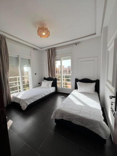 two beds in a room with two windows at Chic Villa - Pool - Wi-Fi -Parking - 3 Bedrooms in Sidi Bouzid