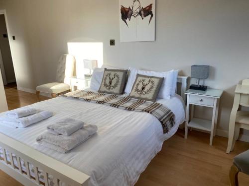 a bedroom with a large white bed with two pillows at Lomond Villa in Balloch