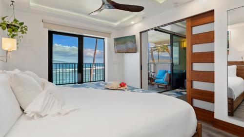 a bedroom with a white bed and a balcony at Spectacular luxury , modern oceanfront condo Maalaea-Kihei ,Maui in Wailuku