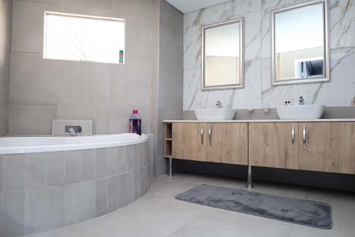 a bathroom with two sinks and a tub and two windows at Lasaro Guest Lodge in Bethlehem