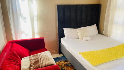 a bedroom with a bed and a red chair at Umthombo guest house in Mbabane