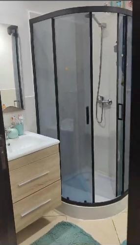 a bathroom with a glass shower with a sink at Garden Beach 2 in Casablanca