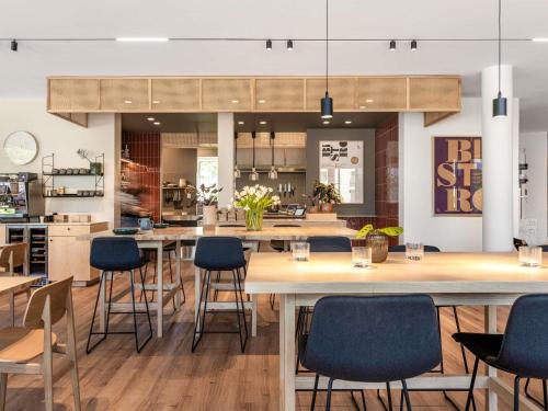 a restaurant with wooden tables and blue chairs at Oru Hub Hotel Tallinn - Handwritten Collection in Tallinn