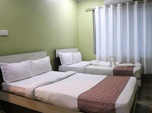 a bedroom with two beds and a window at Brichyalaya Kohalpur in Kohalpur