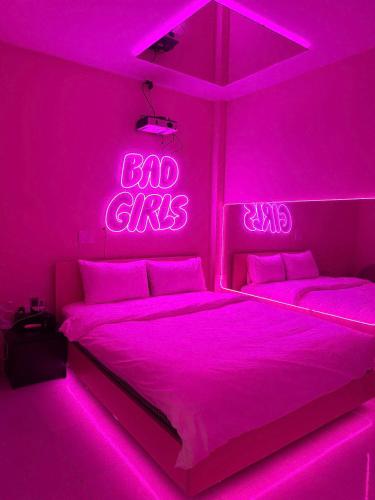 a pink bedroom with two beds and a neon sign at Đào Hoa Love Hotel Đà Nẵng in Danang