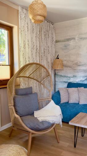 a wicker chair and a couch in a room at Rosa Apartamenty in Dąbki