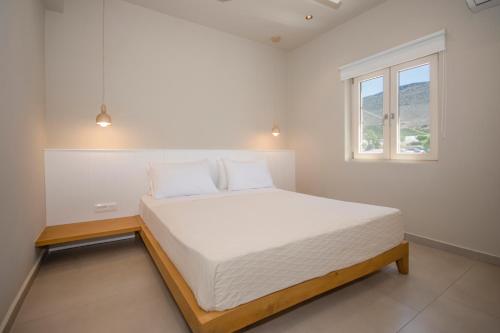 a bedroom with a white bed with a window at Elia Suites in Falasarna
