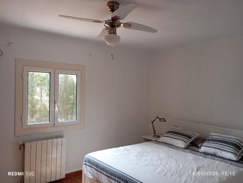 a white bedroom with a ceiling fan and a bed at Private pool and garden in Cunit