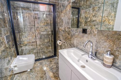 a bathroom with a shower and a sink and a toilet at Royal Batın Apart Otel in Trabzon