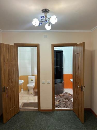 a bathroom with two doors and a toilet at Гостевой дом Достук in Bosteri