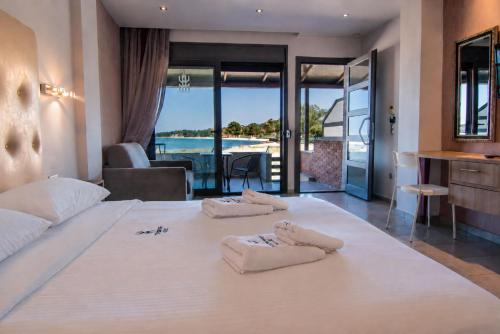 a bedroom with a large white bed with towels on it at Tridente Mare Apart Hotel in Pefkochori