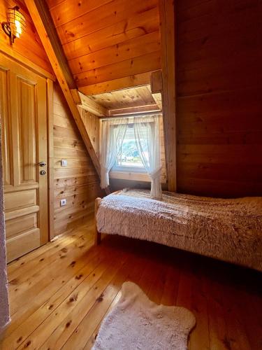 a bedroom with a bed in a wooden room with a window at Apartman Djina Zabljak in Žabljak