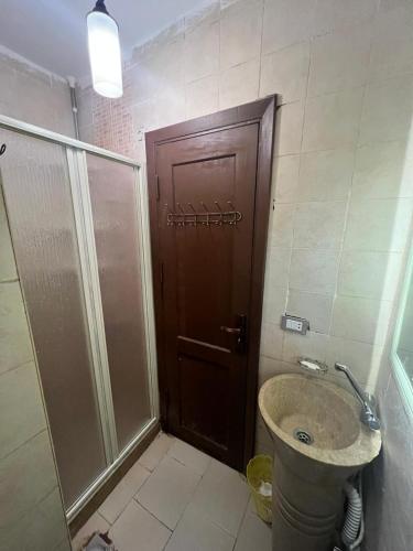 a bathroom with a shower and a sink and a wooden door at Chalet in Belagio Ain Sokhna in Ain Sokhna