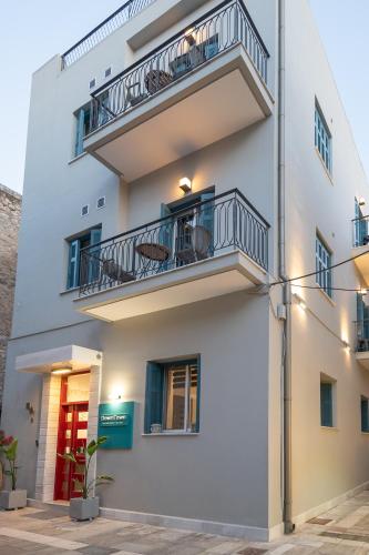 a white building with balconies and a red door at DownTown Hotel in Nafplio