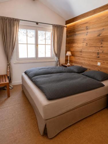 a bedroom with a large bed with a wooden wall at Residence Edelweiss No Stress by Eva in Bellwald