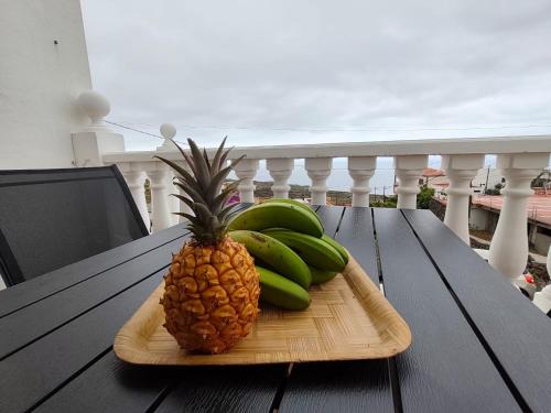 a pineapple and bananas on a wooden plate on a table at Estudio Mary Espectaculares Vistas al Mar in Los Llanillos