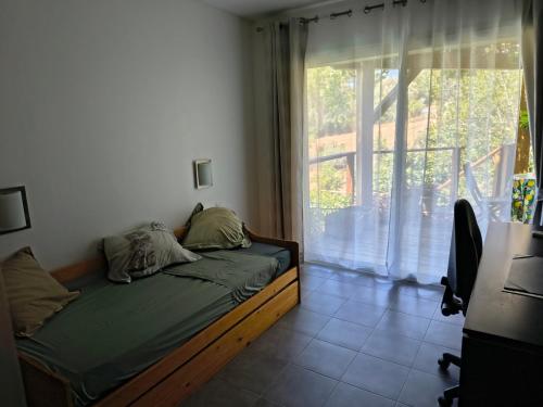 a bed in a room with a large window at Chambre privative in Lecci