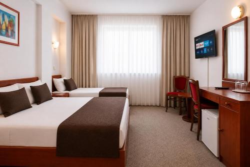 a hotel room with two beds and a desk at Hotel Saraj in Sarajevo