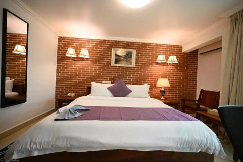 a bedroom with a large bed and a brick wall at Aeroport Grand Hotel in Douala