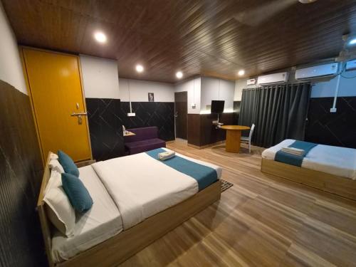 a bedroom with two beds and a desk in a room at Hotel Pohor Regency 10 minutes travel to Kamakhya Temple in Guwahati