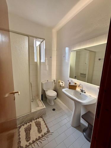 a white bathroom with a sink and a toilet at Hotel Marialena in Ancient Epidauros