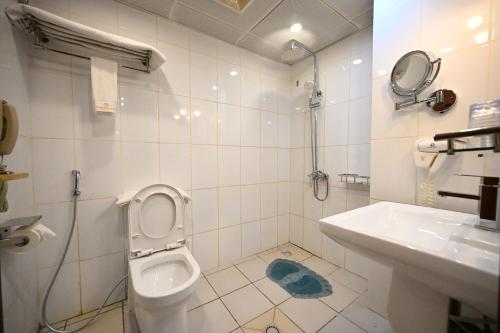 a white bathroom with a toilet and a sink at Aeroport Grand Hotel in Douala
