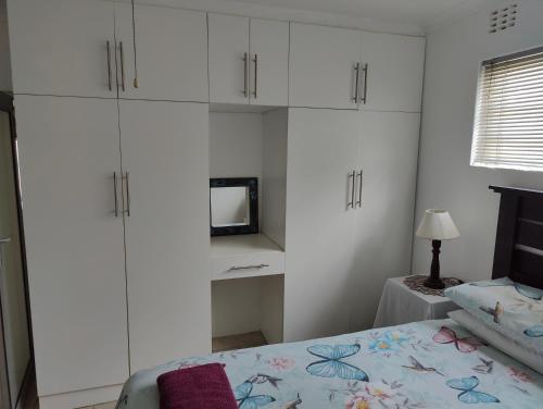 a bedroom with white cabinets and a bed and a tv at Hunters Self Catering Apartment in East London