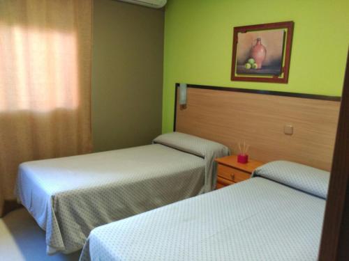 2 camas en una habitación con paredes verdes en Hostal DS, en Velilla de San Antonio