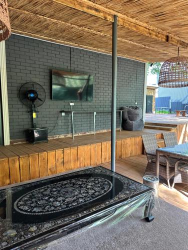a large patio with a tv and a table at Отдых у речки in Almaty
