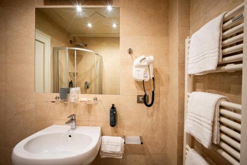 a bathroom with a sink and a mirror and towels at Hotel Esplanade in Marina di Pietrasanta
