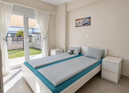 a bed in a room with a large window at Lagonisi Apartment in Skála Nikíta