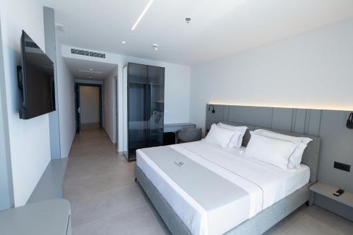 a bedroom with a white bed and a flat screen tv at White Amfora Hotel in Shëngjin