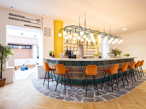 eine Bar in einem Restaurant mit orangefarbenen Stühlen in der Unterkunft Mercure Brussels Centre Rogier in Brüssel