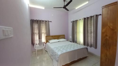 a bedroom with a bed and a chair in it at Kodikkakkam Homestay in Kappil