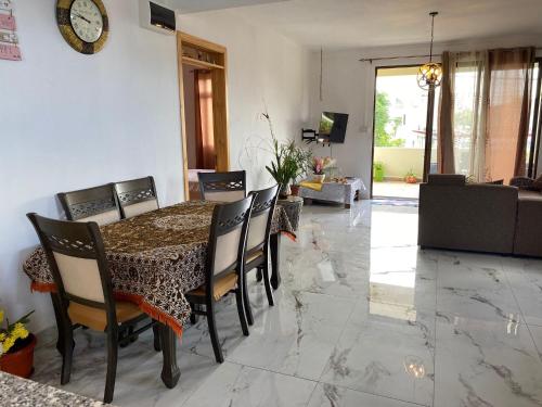 a dining room table with chairs and a clock on the wall at villa POOJA in Cap Malheureux