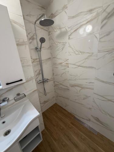 a white bathroom with a shower and a sink at Cozy Home 2 Bedroom apartment in Kyustendil