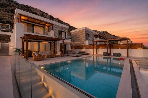 a villa with a swimming pool in front of a house at Elements Villas in Lartos