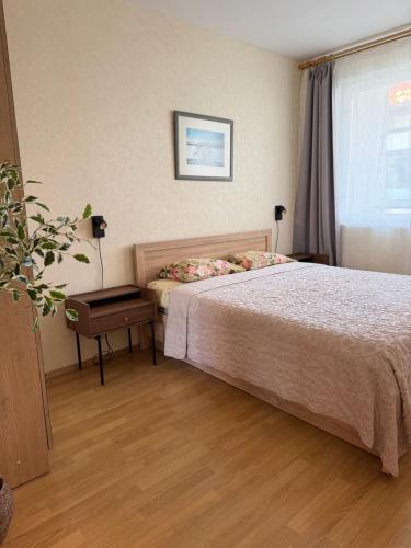 a bedroom with a bed and a table and a window at Apartment Jūros Mėlis in Nida