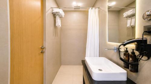 a bathroom with a white sink and a shower at Vaishnavi Beacon Hotel Patna in Patna