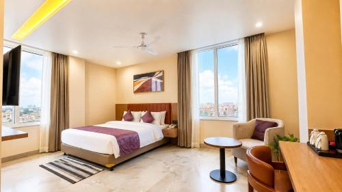 a hotel room with a bed and a chair and windows at Vaishnavi Beacon Hotel Patna in Patna