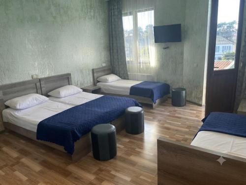 a bedroom with two beds with blue sheets and a television at Guramishvili 7 in Kobuleti