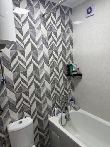 a bathroom with a white toilet and a checkered wall at Гостевой дом 64 in Naryn