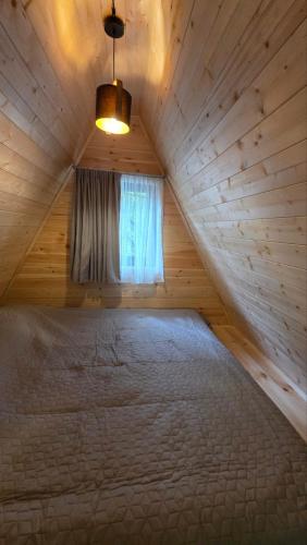 a large bed in a wooden room with a window at Riverside Ghari Cottages in Oni